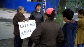 Image for article M. Li Shaotie dans un état critique suite à la persécution--Sa vieille mère tient une pancarte dans la rue pour solliciter de l'aide